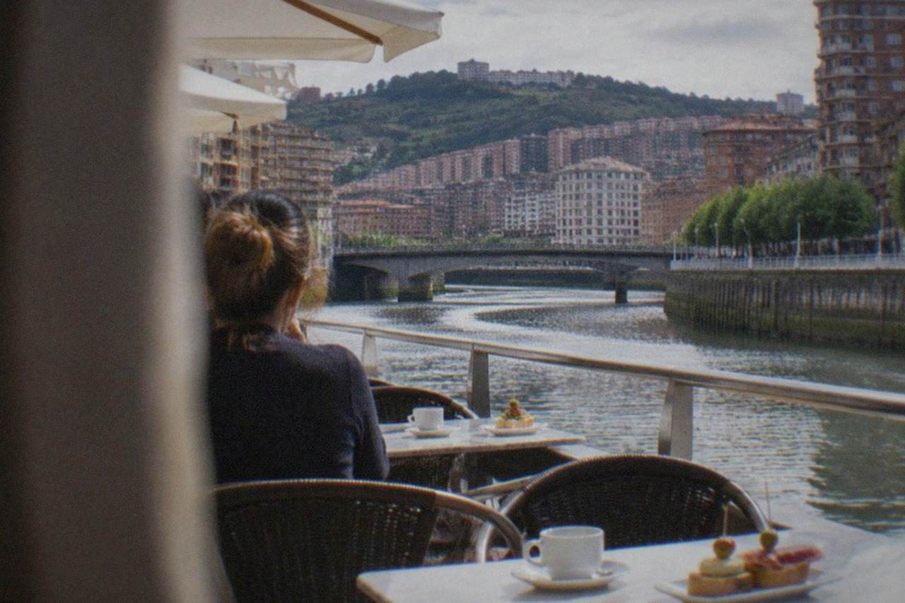 A sunny morning café terrace in Bilbao with coffee cups and pintxos plates on marble tables