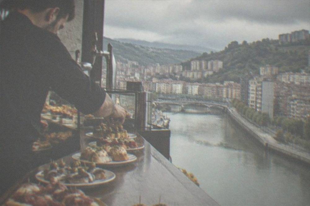 A barman setting out fresh pintxos on a counter in a Bilbao tavern