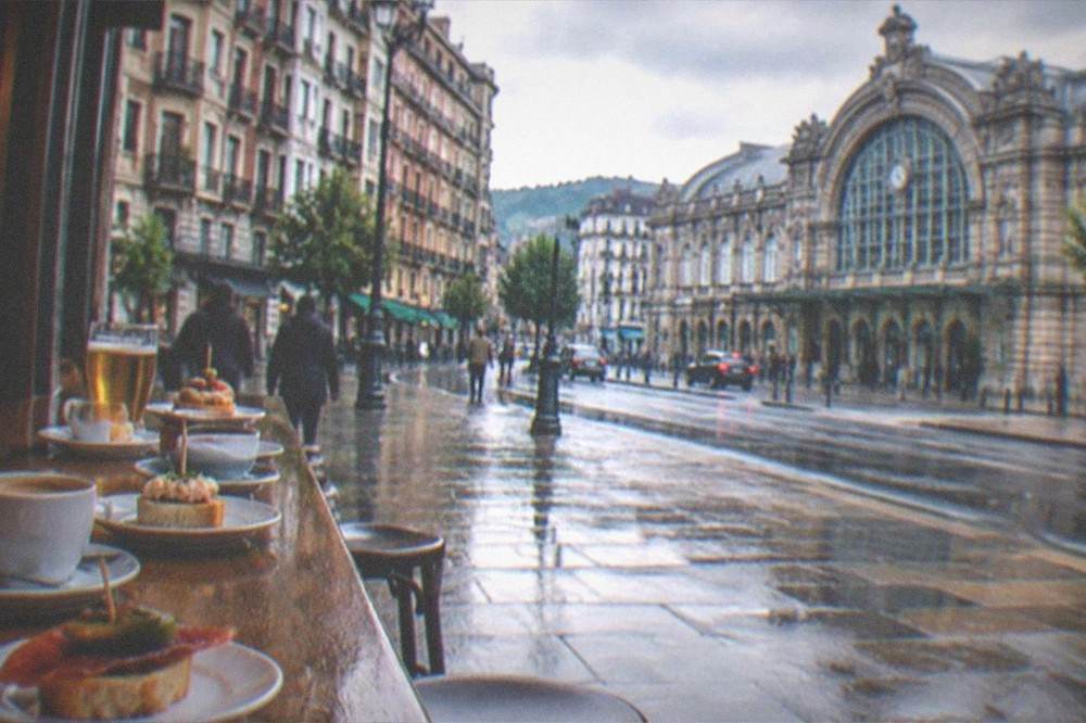A row of coffee cups and small pintxo plates lined along a wooden bar top
