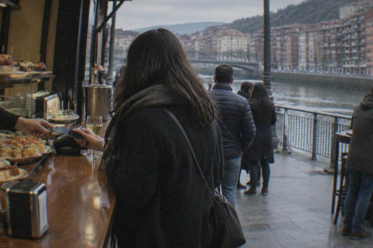 A customer paying with a contactless card at a busy pintxos bar counter in Bilbao's Old Town