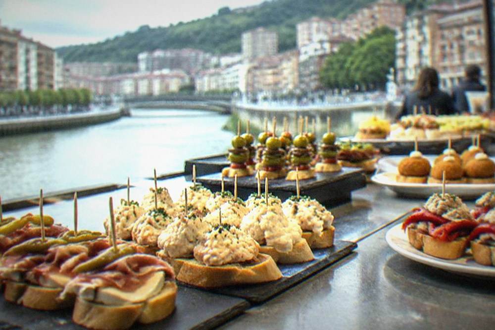 Rows of pintxos displayed on a bar counter with small price signs in Bilbao