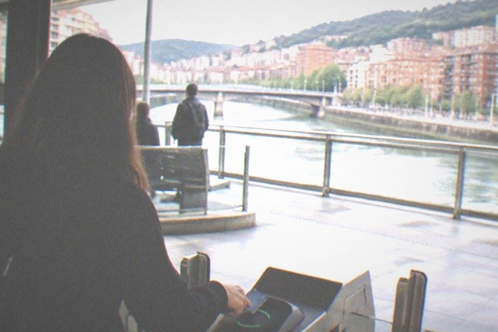 A traveler tapping a contactless card on a metro validator inside a Bilbao station