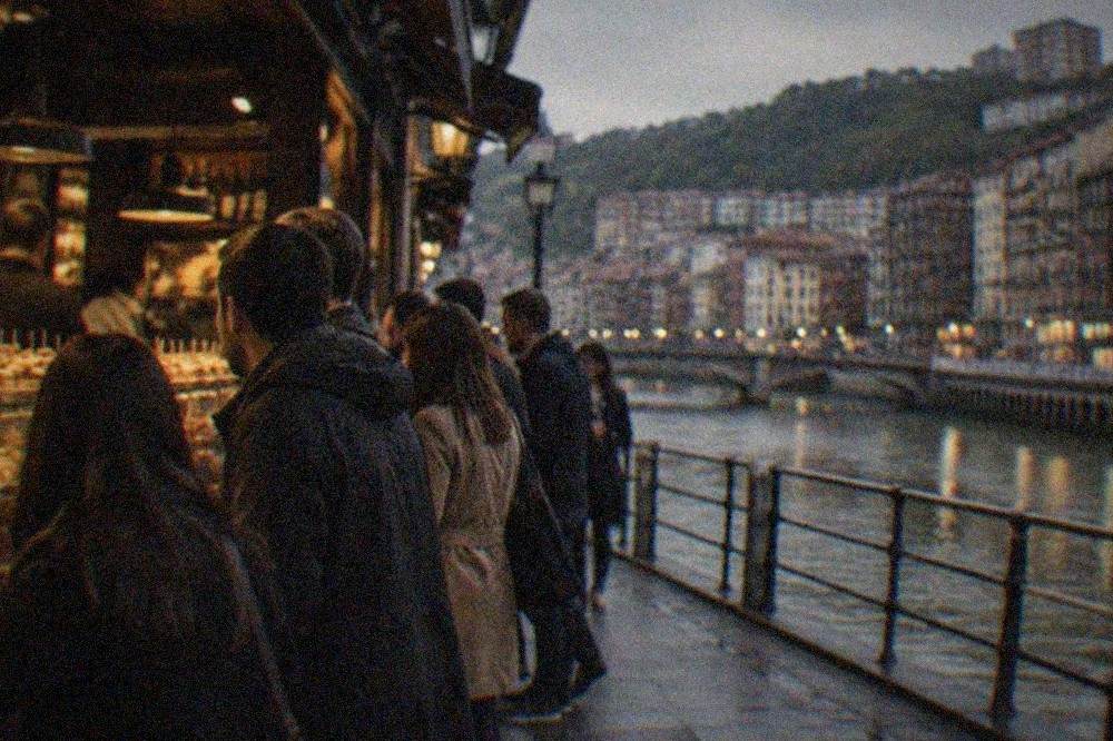 A busy pintxos bar in Bilbao's Old Town at night with people standing at the counter
