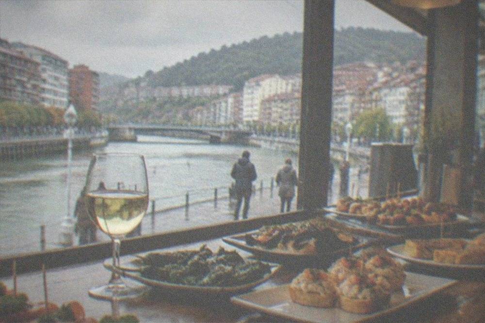 A pintxos bar counter in Bilbao loaded with small seasonal Basque dishes and glasses of txakoli