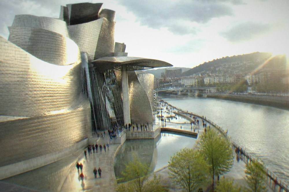 Visitors entering the tall atrium of the Guggenheim Museum Bilbao on a busy afternoon