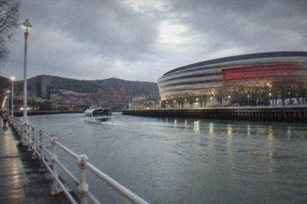 Evening view of San Mames stadium lit up beside the Nervion river in Bilbao