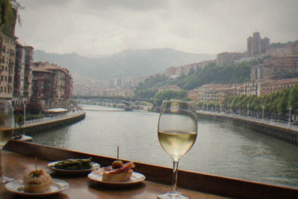 Two wine glasses and small pintxo plates on a wooden bar counter in an Old Town Bilbao tavern