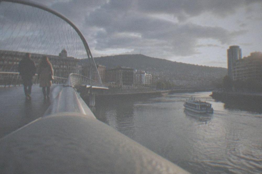 A couple crossing the Zubizuri footbridge over the Nervion river on a bright morning in Bilbao