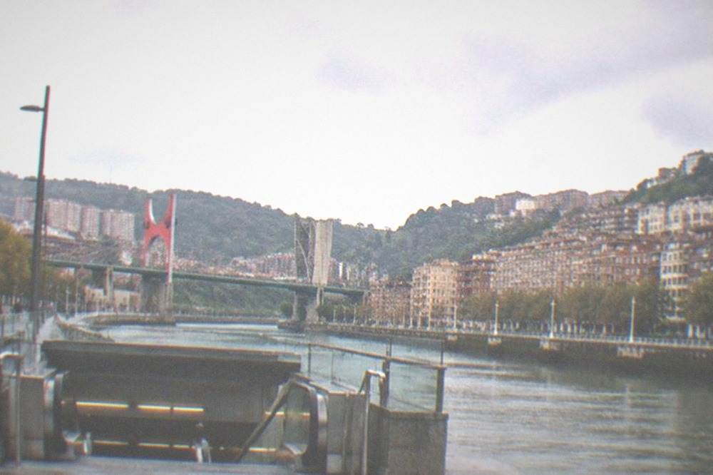 A metro station entrance in Bilbao with a bilingual sign above the escalators