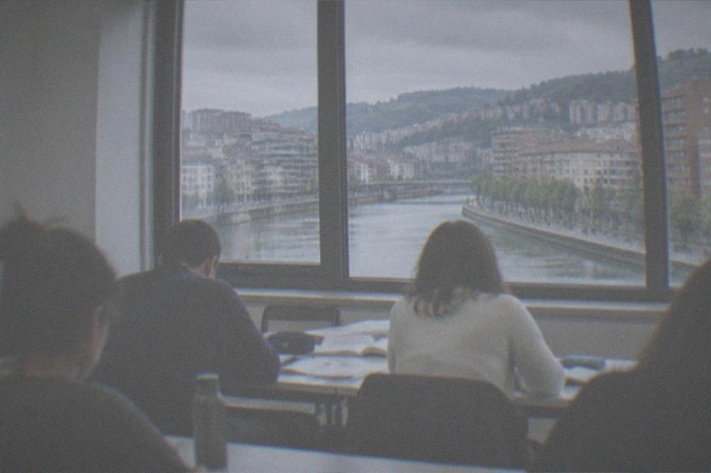 A language classroom with adult students working through exercise books at shared tables