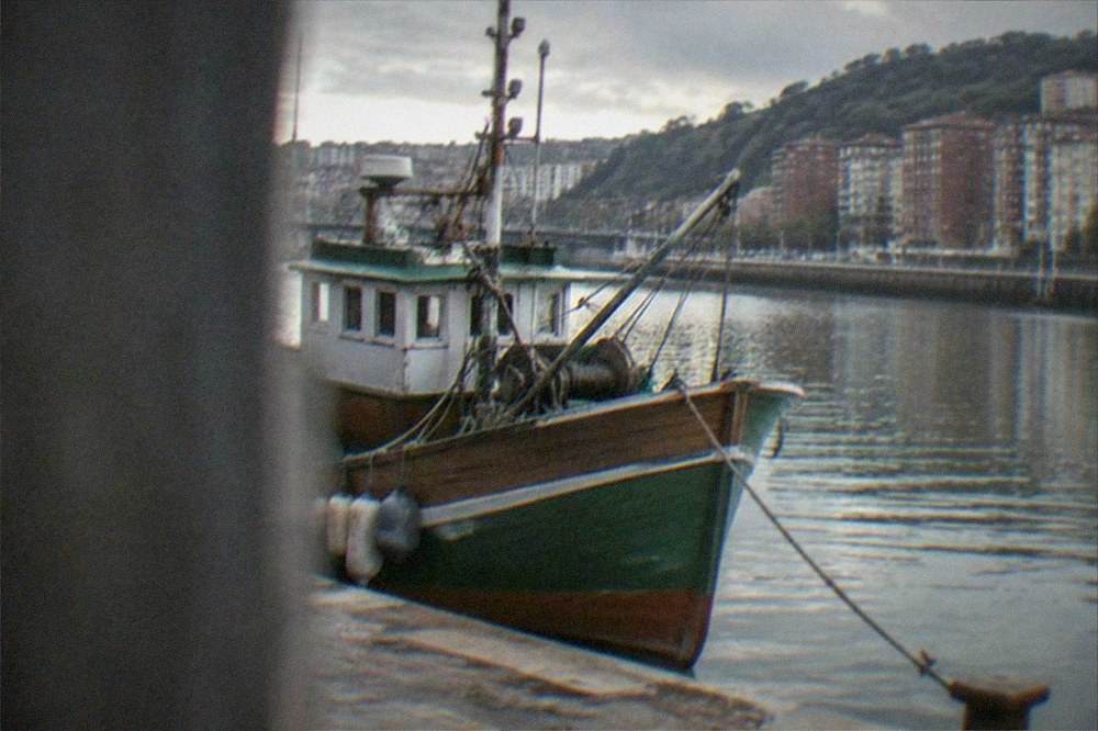 A wooden fishing boat with a Basque name painted on the hull moored in a Bizkaia harbor