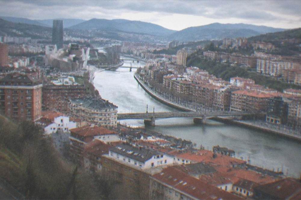 A panoramic view over Bilbao's rooftops with the estuary winding toward the mountains