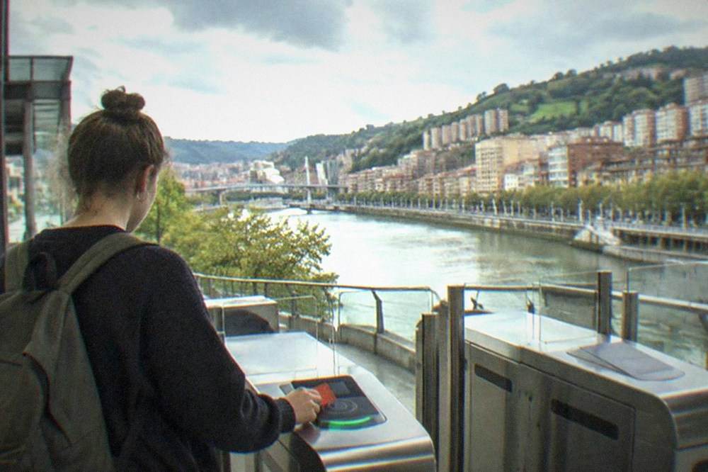 A student tapping a Barik card at a metro station gate in Bilbao