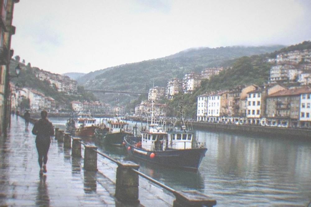 Fishing boats moored in the harbour at Bermeo with Basque signage on a warehouse wall