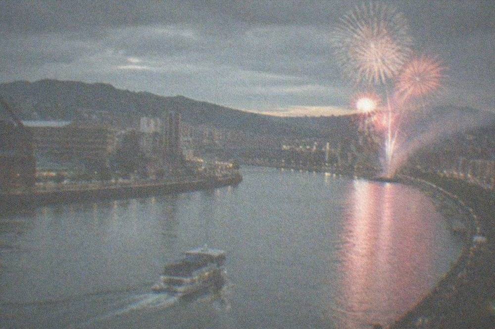 Crowds watching fireworks over the Nervion river during Bilbao's Aste Nagusia festival at night