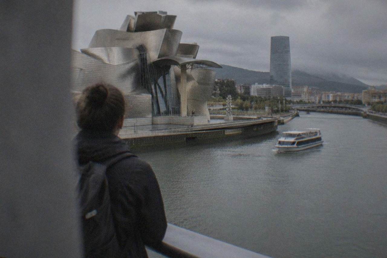 Traveler with a backpack looking out over the Guggenheim Museum and the Nervion estuary in Bilbao