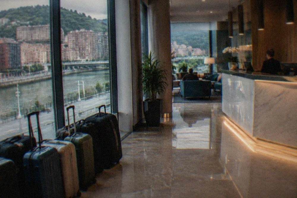 Suitcases lined up in a bright hotel lobby with a reception desk