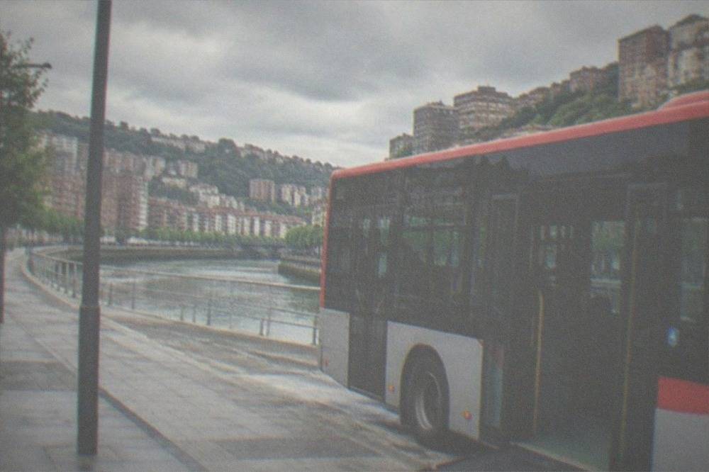 A low-floor Bilbao city bus at a stop with a ramp deployed on a flat street