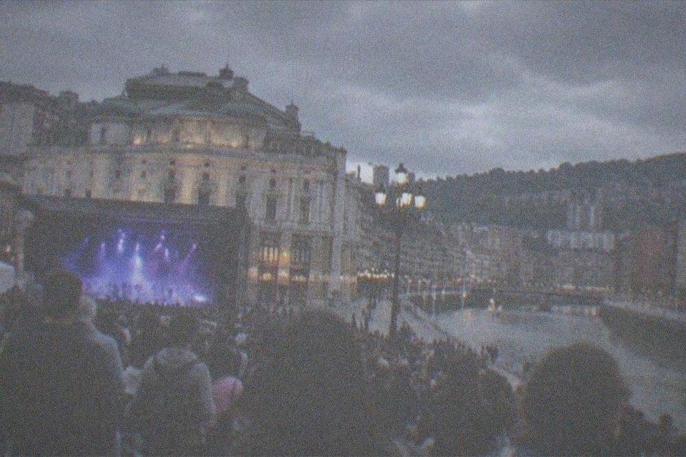 Crowds gathered at night in Plaza Arriaga during Bilbao's Aste Nagusia festival with lights and a concert stage