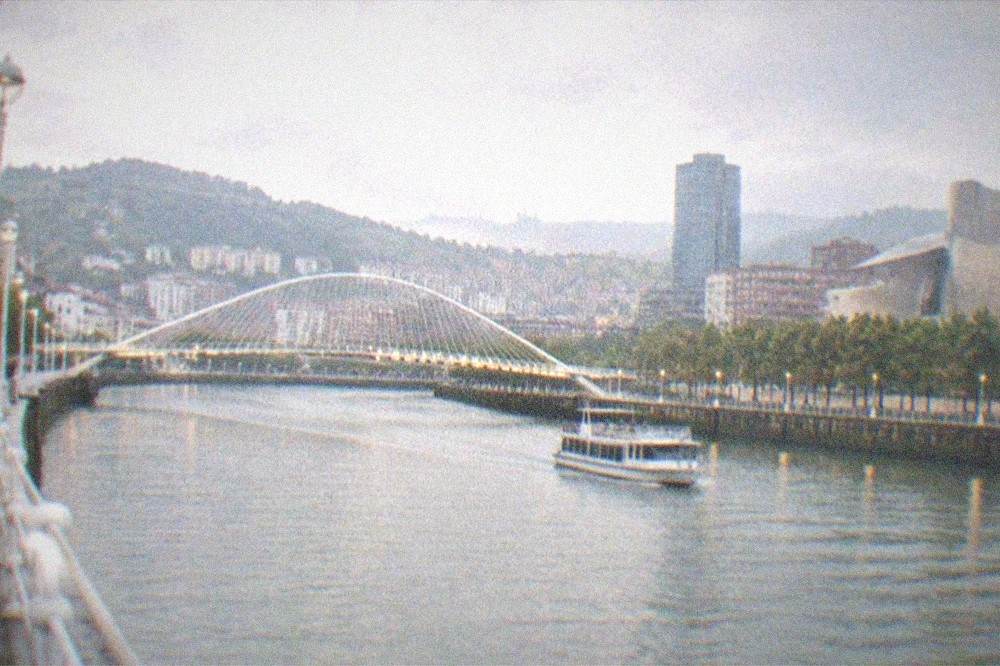 An evening view of the illuminated Zubizuri bridge and Nervion estuary waterfront in Bilbao