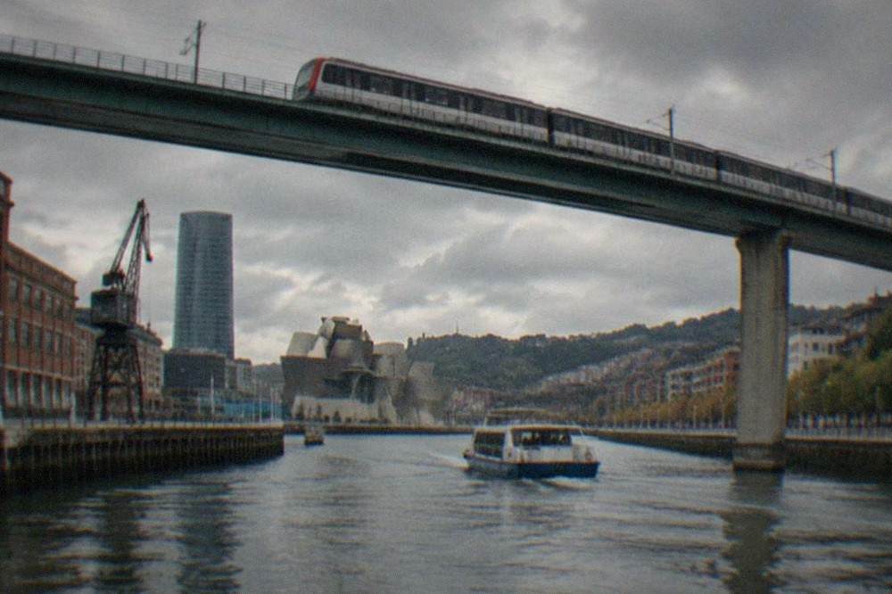 A metro train crossing an elevated viaduct above the Nervion estuary in Bilbao