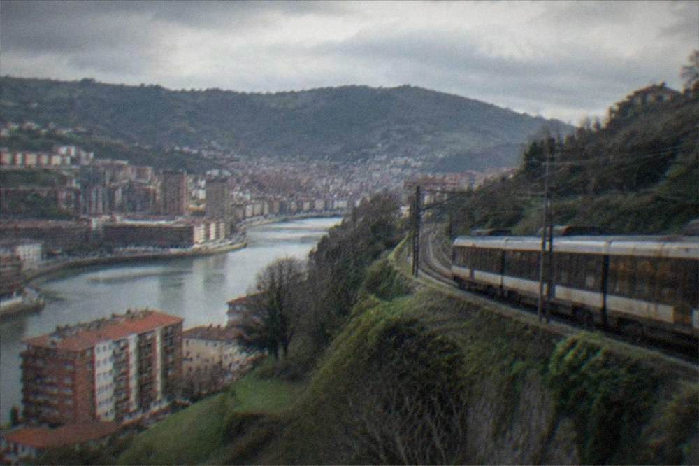 A train passing green Basque hills on a coastal line near the Bay of Biscay