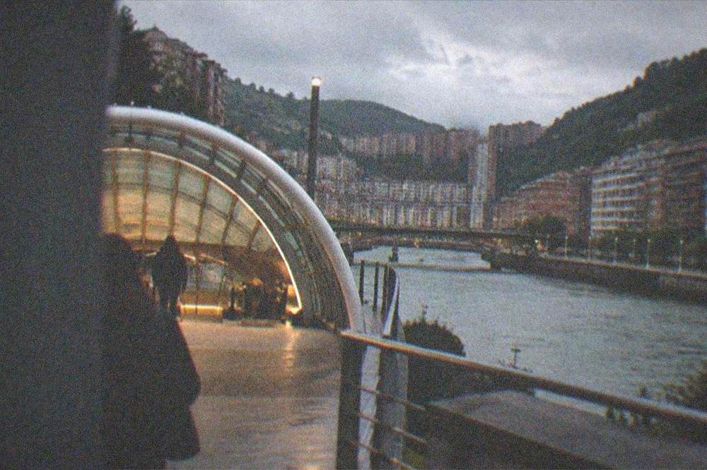The illuminated curved entrance of a Foster-designed Bilbao Metro station at dusk