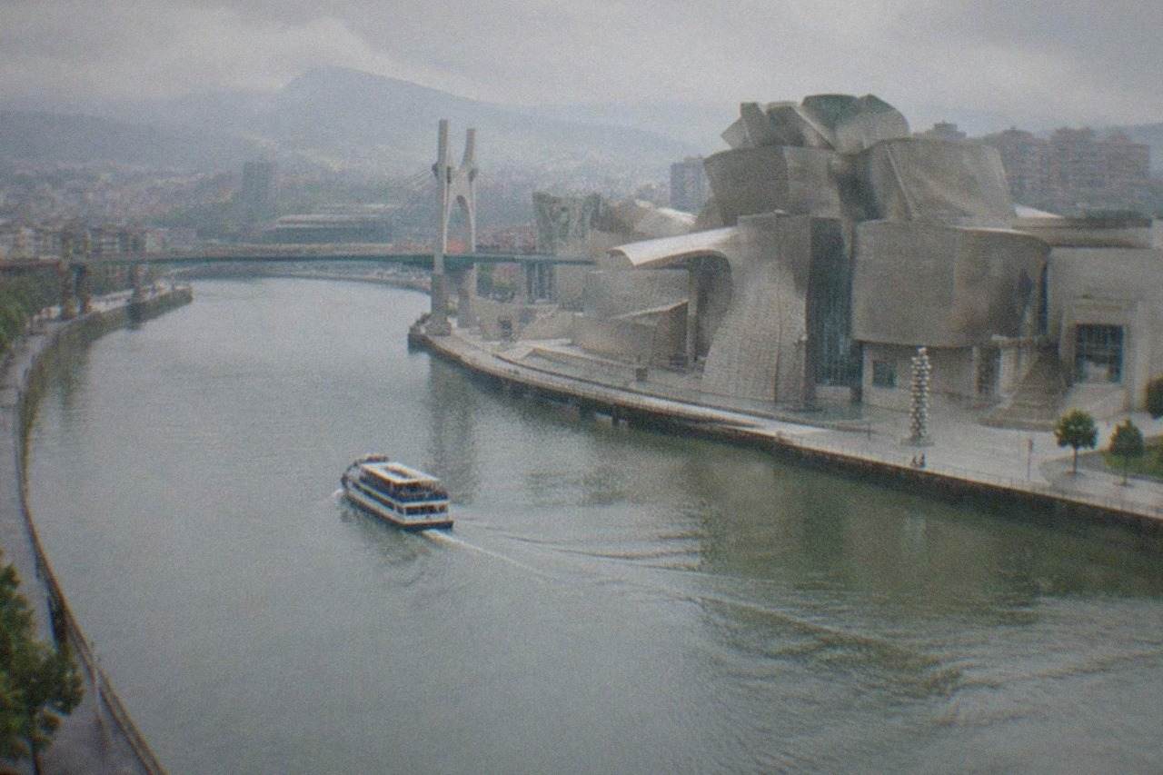 The titanium curves of the Guggenheim Museum Bilbao beside the Nervion estuary on a bright day