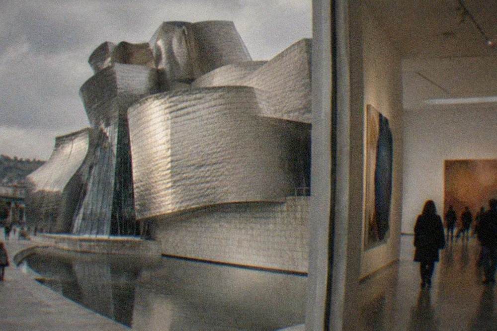 Visitors walking through a bright museum gallery with large contemporary paintings on the walls