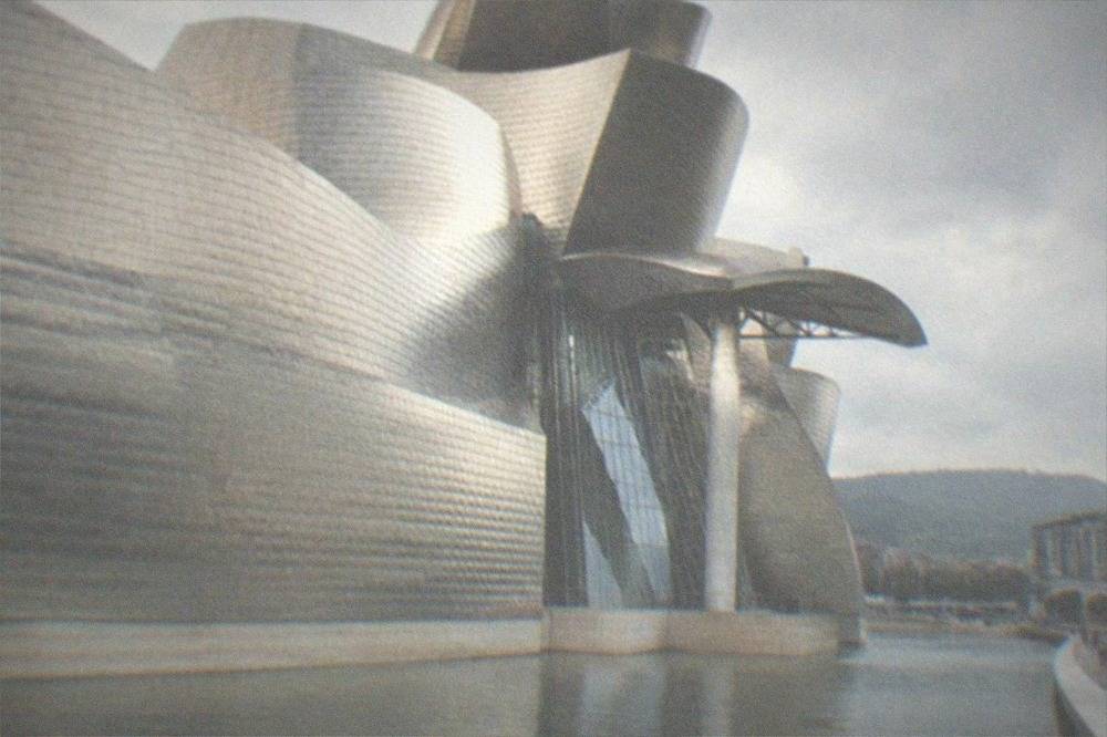 The exterior of the Guggenheim Museum Bilbao with its reflective titanium panels beside the water