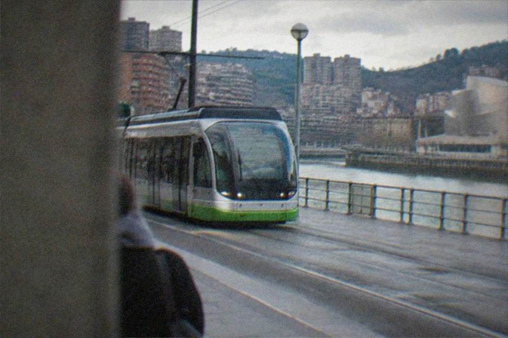 A tram passing modern buildings along a Bilbao street near the museum district