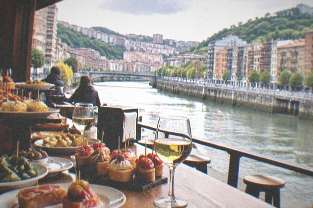 A lively pintxos bar counter crowded with small plates and glasses of wine in Bilbao