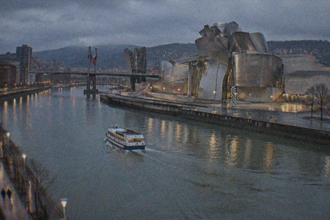 Bilbao's Guggenheim Museum glowing beside the Nervion river on a December evening