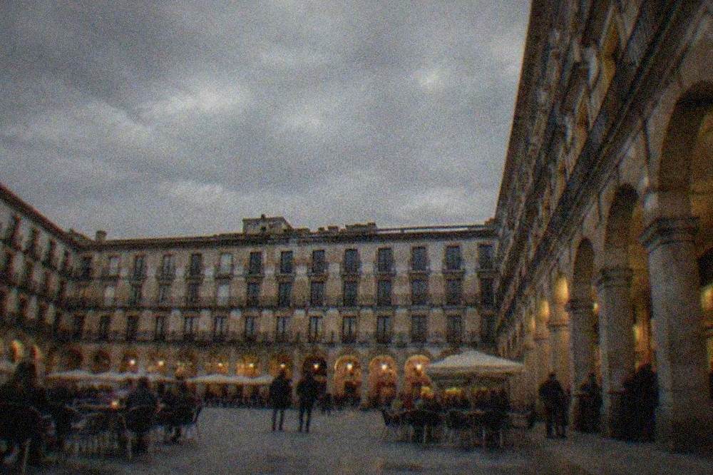 Plaza Nueva in Bilbao's Old Town with lit arcades and people at evening bar counters