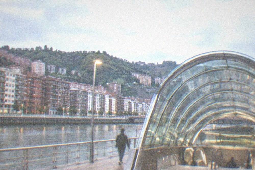 A Metro Bilbao station entrance with the Fosterito glass canopy lit at night