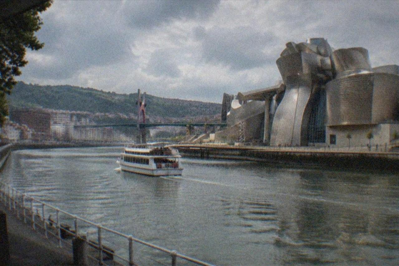 Evening view over the Nervion river in Bilbao with illuminated buildings and the Guggenheim Museum glowing along the waterfront