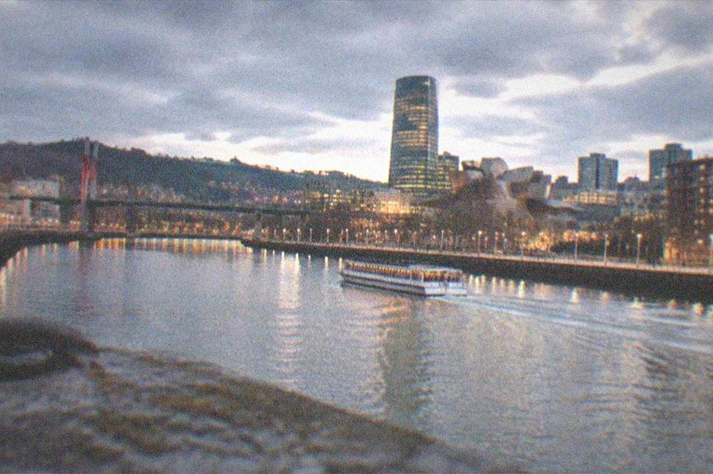 Wide night panorama of central Bilbao with lit bridges over the Nervion river and the illuminated city skyline