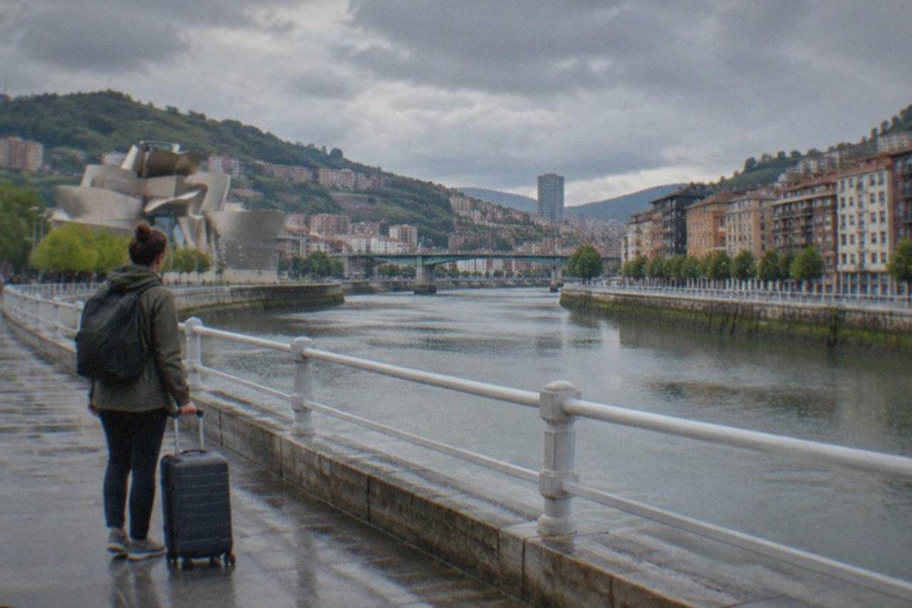 A packed suitcase with a rain jacket, walking shoes and a city map on a wooden floor