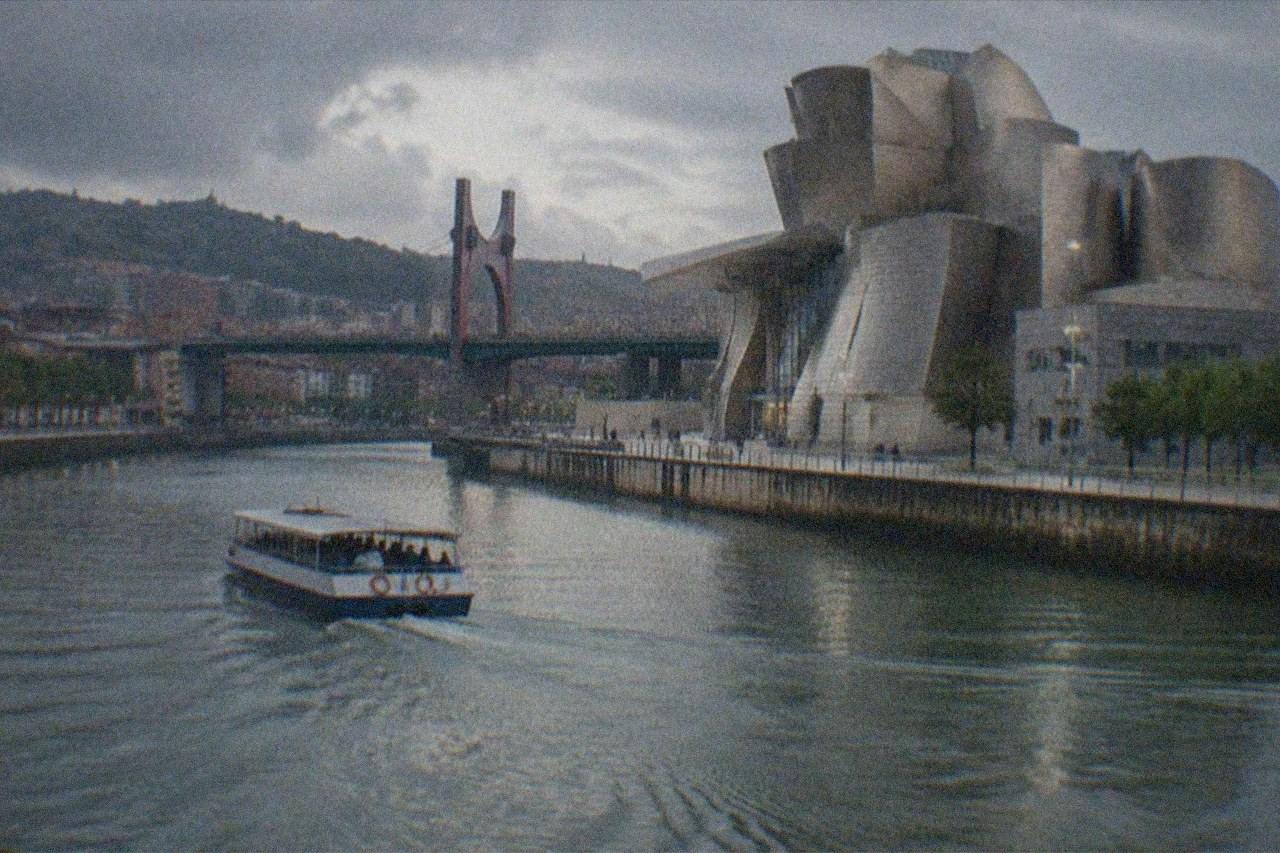The Guggenheim Museum Bilbao titanium curves beside the Nervion river at dusk