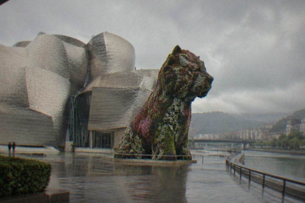 Flower sculpture of a puppy standing in front of the Guggenheim Museum on a grey day