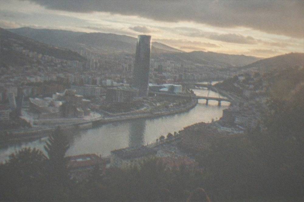 The Bilbao skyline seen from the Artxanda hillside at sunset, with the estuary curving through the city