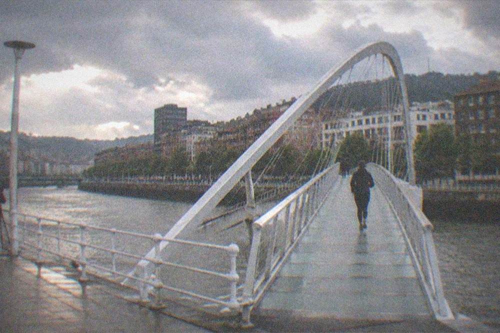 A photographer with a tripod on a riverside promenade beside the estuary in the evening