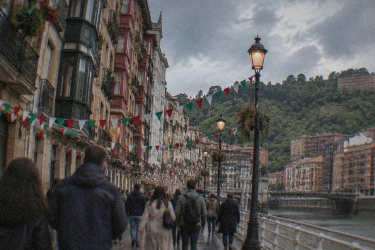 Festively decorated street in central Bilbao with crowds walking under banners and string lights