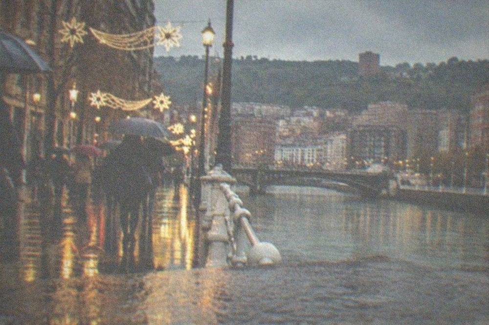 Decorated Christmas street lights over a rainy evening in central Bilbao with umbrellas in the crowd