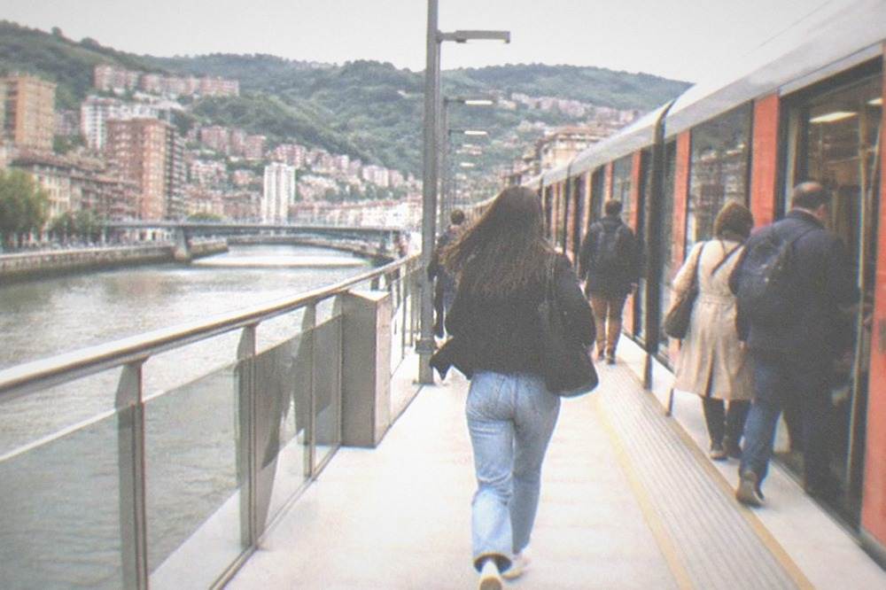 Passengers boarding a modern metro train at a bright Bilbao station platform