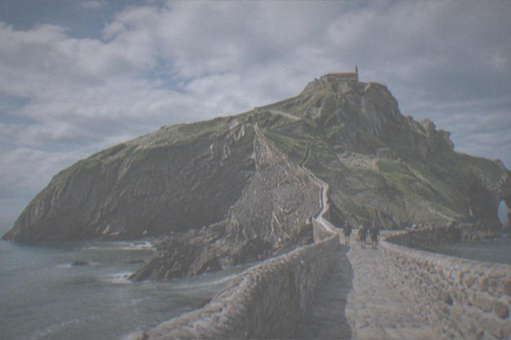 Stone causeway leading across the sea to the hermitage on the Gaztelugatxe islet under a clear sky