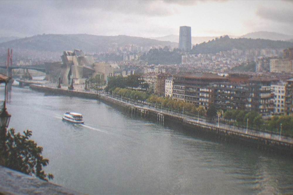 Wide view over Bilbao's rooftops and the Nervion estuary in warm late afternoon light