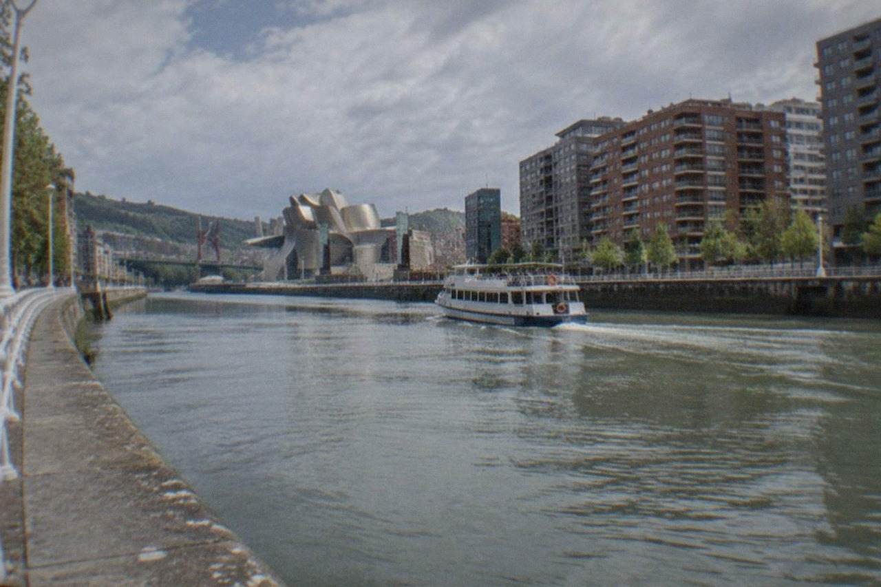 Modern apartment buildings along the Nervion river in Bilbao with the Guggenheim Museum in the distance