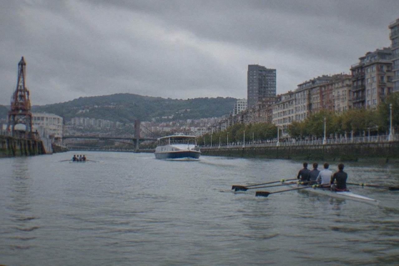 Rowing crews training on the Nervion estuary in Bilbao with riverside buildings behind them