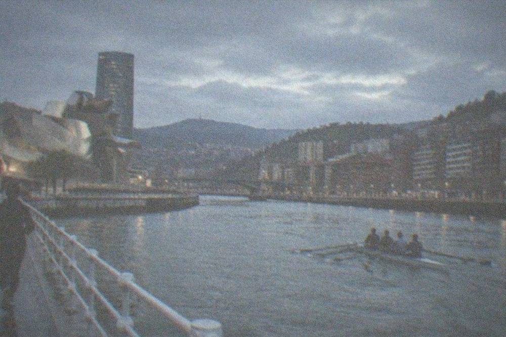Rowing boat cutting through choppy Atlantic water near a Basque coastal headland